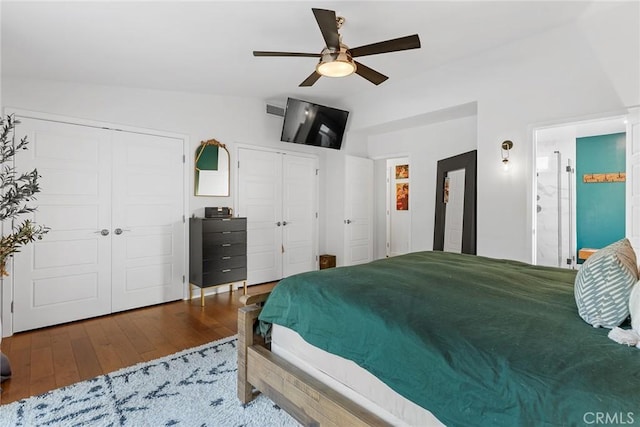 bedroom featuring hardwood / wood-style floors, ceiling fan, lofted ceiling, and two closets