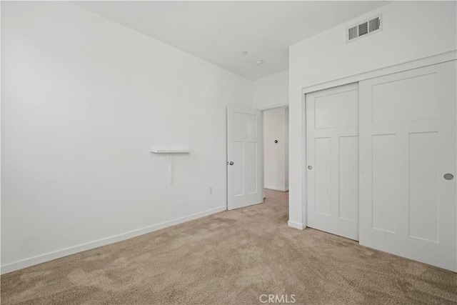 unfurnished bedroom featuring light carpet and a closet