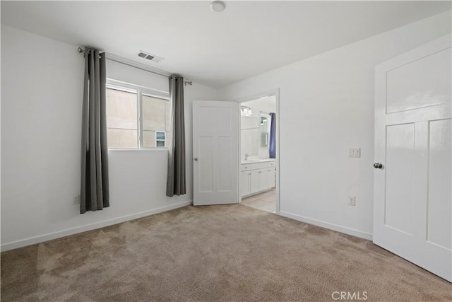 unfurnished bedroom featuring light carpet, ensuite bathroom, and sink