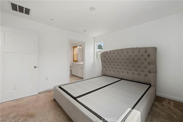 bedroom with ensuite bathroom, sink, and light carpet