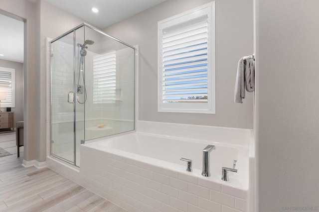 bathroom featuring a healthy amount of sunlight, hardwood / wood-style flooring, and shower with separate bathtub