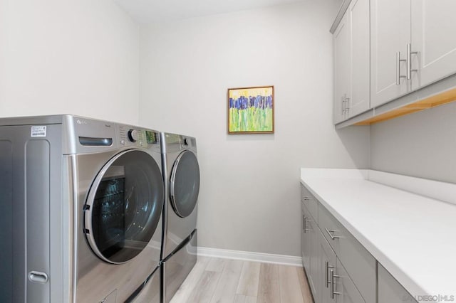 clothes washing area featuring cabinets, light hardwood / wood-style floors, and independent washer and dryer