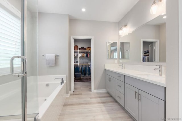 bathroom featuring vanity, wood-type flooring, and a relaxing tiled tub