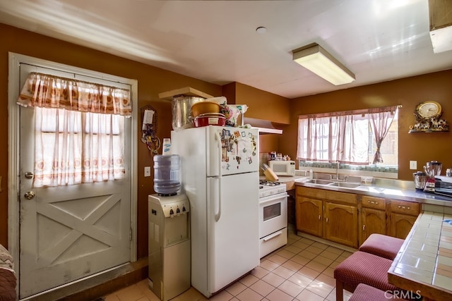 kitchen with tile counters, sink, extractor fan, white appliances, and light tile patterned floors