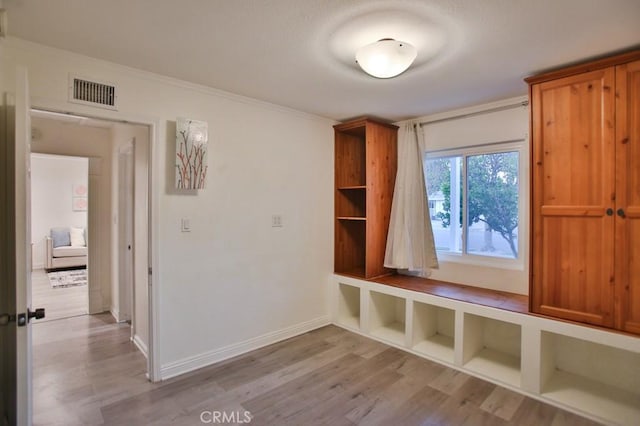 mudroom with light wood-type flooring and crown molding