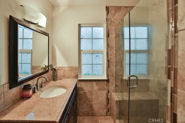 bathroom featuring tile walls, a shower with door, and vanity