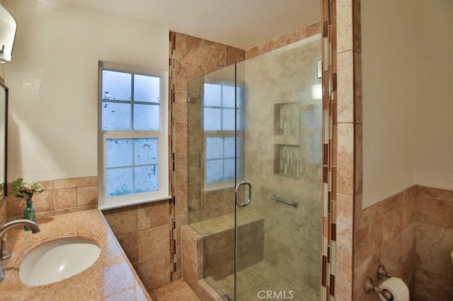 bathroom featuring vanity, tile walls, and a shower with door