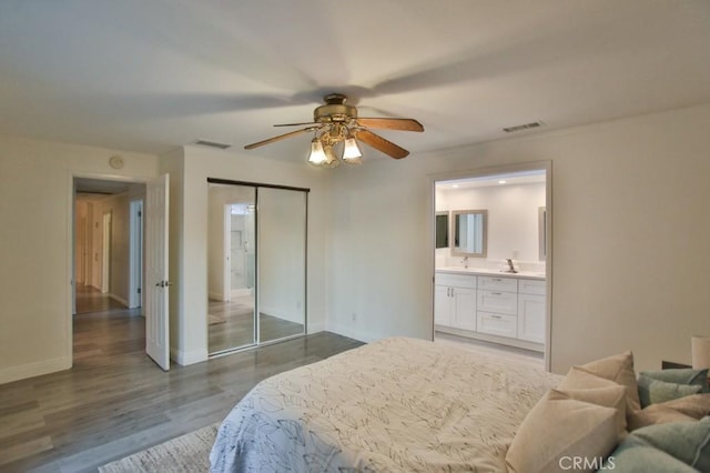 bedroom with ceiling fan, ensuite bath, dark wood-type flooring, a closet, and sink