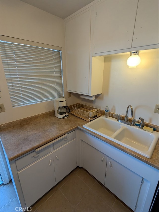 kitchen with white cabinets, sink, and light tile patterned flooring