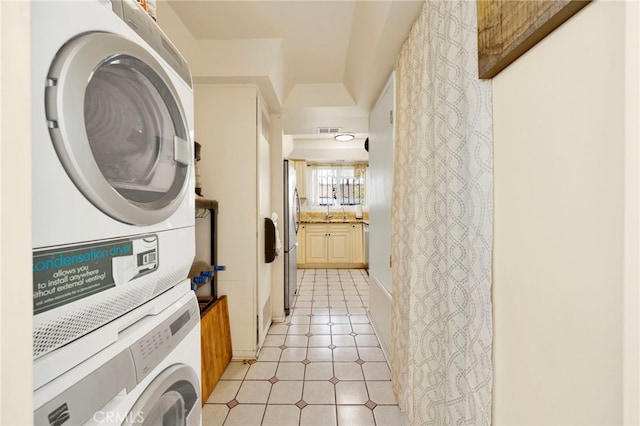 laundry room with light tile patterned flooring and stacked washer / dryer