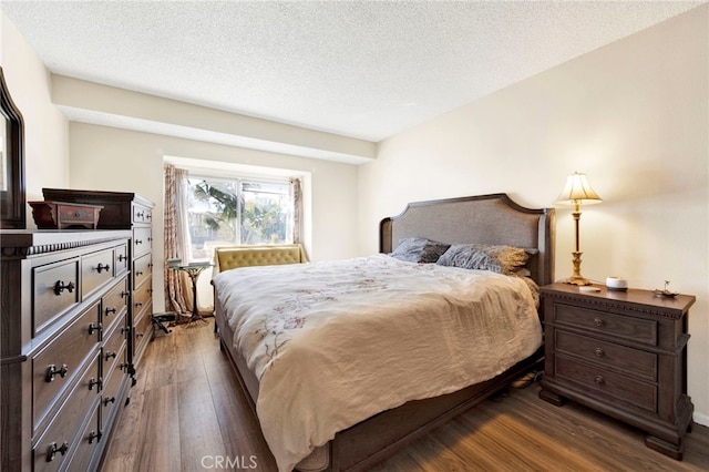 bedroom with dark hardwood / wood-style floors and a textured ceiling