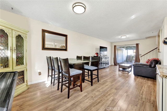 dining space featuring light wood-type flooring and a textured ceiling