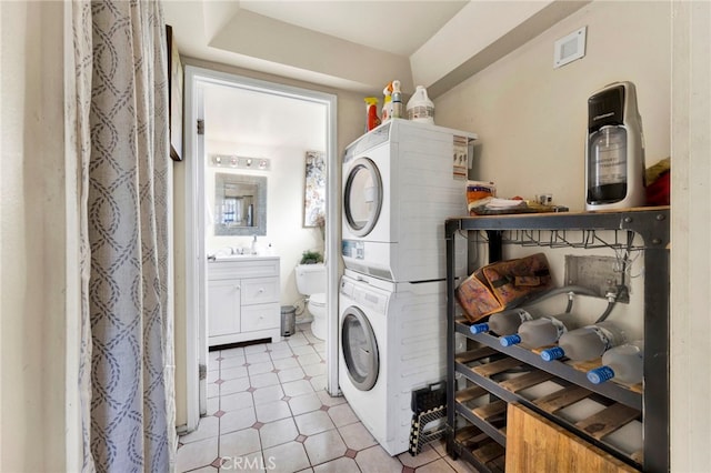 laundry area with light tile patterned floors and stacked washer and clothes dryer