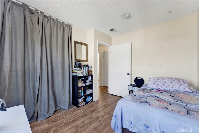 bedroom with a textured ceiling and hardwood / wood-style flooring