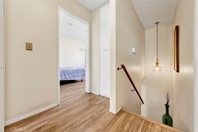 corridor with light hardwood / wood-style floors and a textured ceiling