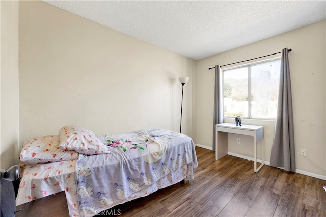 bedroom featuring a textured ceiling and dark hardwood / wood-style flooring