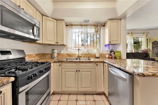 kitchen featuring cream cabinetry, stainless steel appliances, a wealth of natural light, and sink