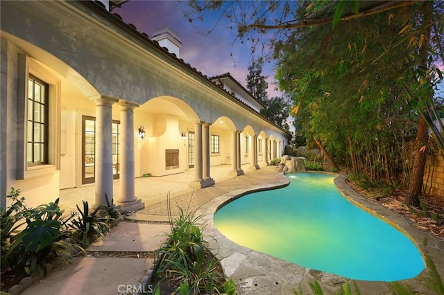 pool at dusk featuring a patio