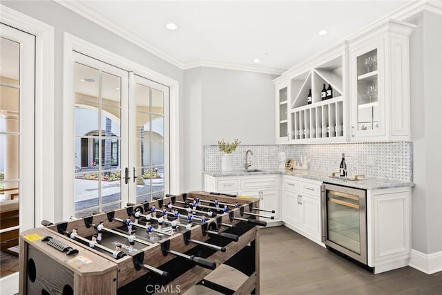 kitchen with light stone countertops, beverage cooler, sink, light hardwood / wood-style floors, and white cabinetry