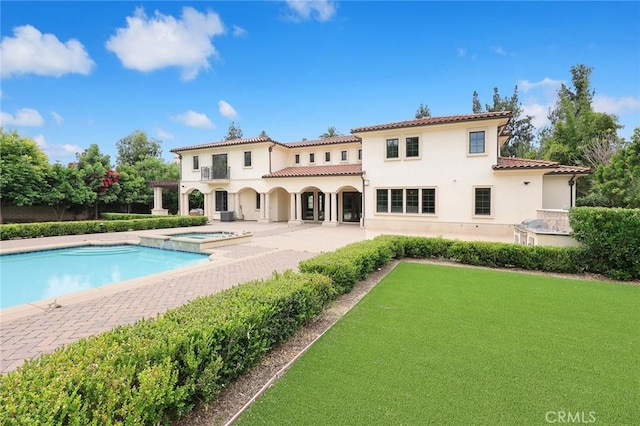 rear view of house with a pool with hot tub and a patio area