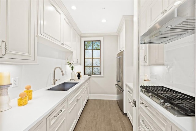 kitchen featuring crown molding, sink, light wood-type flooring, appliances with stainless steel finishes, and white cabinetry