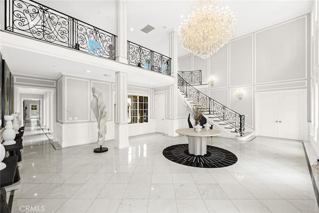 entrance foyer with a high ceiling, light tile patterned floors, and an inviting chandelier