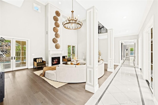 living room with plenty of natural light, light hardwood / wood-style floors, french doors, and a notable chandelier