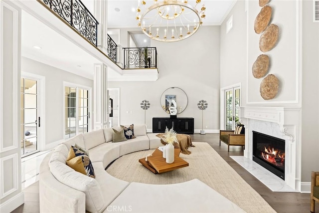 living room featuring a chandelier, a towering ceiling, wood-type flooring, and ornamental molding