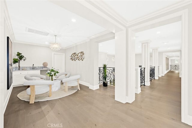 living room with a chandelier, light hardwood / wood-style flooring, crown molding, and sink