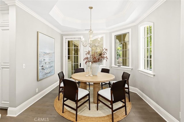 dining area featuring a tray ceiling, a notable chandelier, dark hardwood / wood-style floors, and ornamental molding