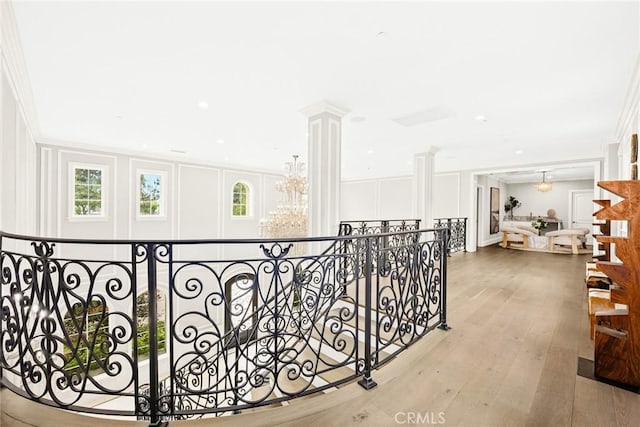 corridor with ornamental molding, light hardwood / wood-style flooring, and decorative columns