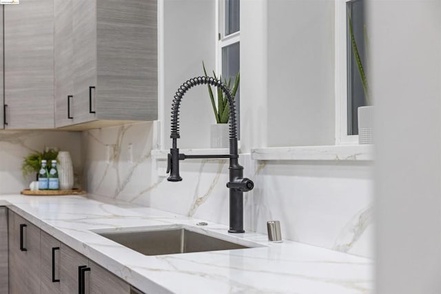 interior details with light stone countertops, sink, and tasteful backsplash