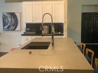 kitchen with sink, white cabinetry, and a kitchen island with sink