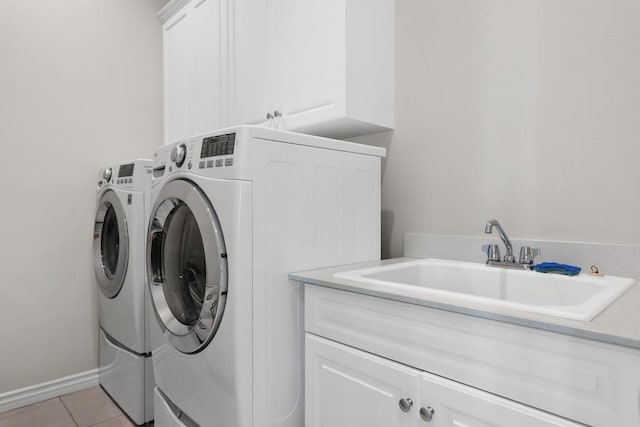 laundry area with cabinets, light tile patterned floors, sink, and washing machine and clothes dryer