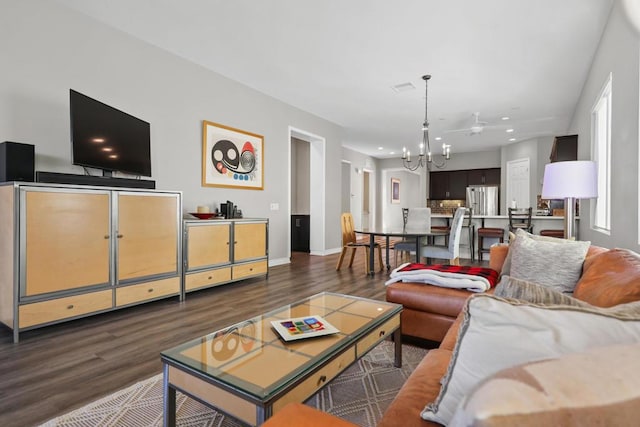 living room with ceiling fan with notable chandelier and dark hardwood / wood-style flooring