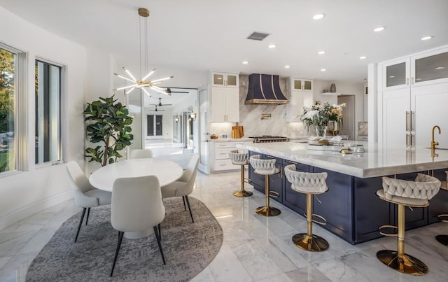 kitchen with white cabinetry, wall chimney exhaust hood, decorative backsplash, and a spacious island