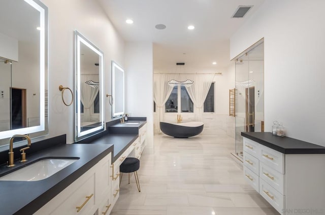 bathroom featuring vanity and independent shower and bath