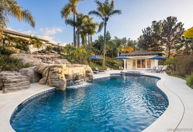 view of swimming pool with pool water feature, a patio area, and an outdoor structure