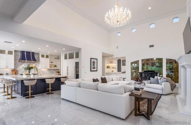 living room with a high ceiling, ornamental molding, and an inviting chandelier