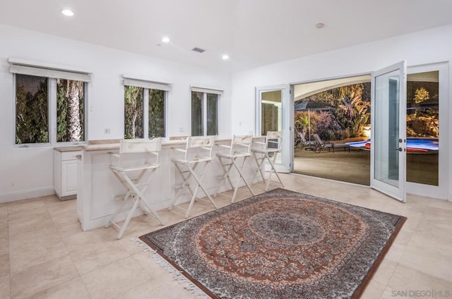 interior space featuring light tile patterned floors, a kitchen bar, white cabinets, and a center island