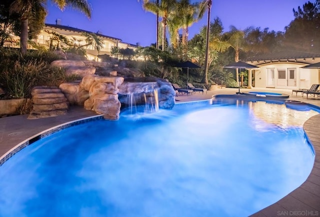 pool at dusk with an in ground hot tub