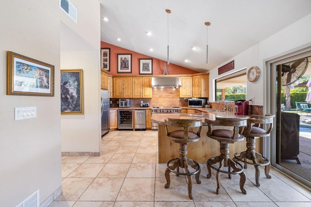 kitchen featuring stainless steel appliances, wall chimney range hood, a kitchen breakfast bar, high vaulted ceiling, and kitchen peninsula