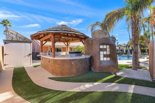 view of patio featuring a gazebo, area for grilling, central AC unit, and exterior kitchen