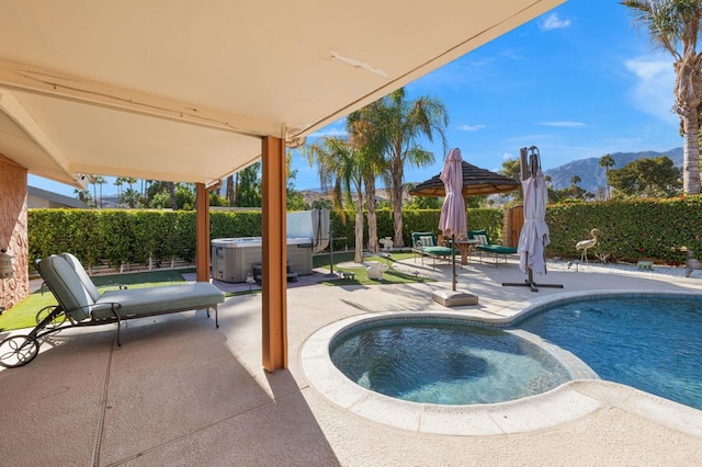 view of swimming pool featuring a mountain view, a hot tub, and a patio area