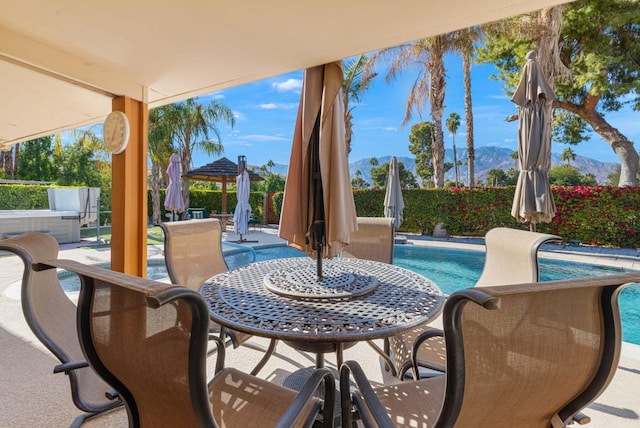 view of patio featuring a mountain view and a swimming pool with hot tub