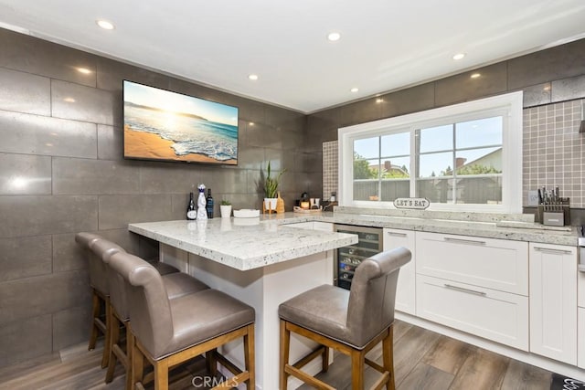 bar with tile walls, white cabinetry, beverage cooler, and dark hardwood / wood-style floors