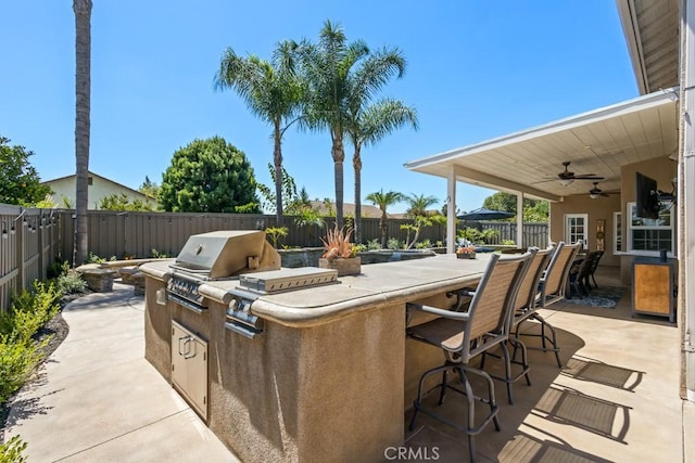 view of patio / terrace featuring ceiling fan, a grill, an outdoor bar, and exterior kitchen