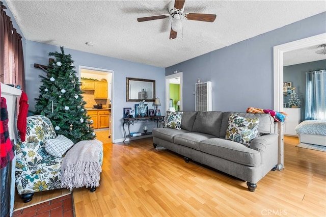 living room featuring wood-type flooring, a textured ceiling, and ceiling fan