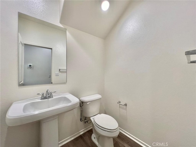 bathroom featuring wood-type flooring, toilet, and lofted ceiling