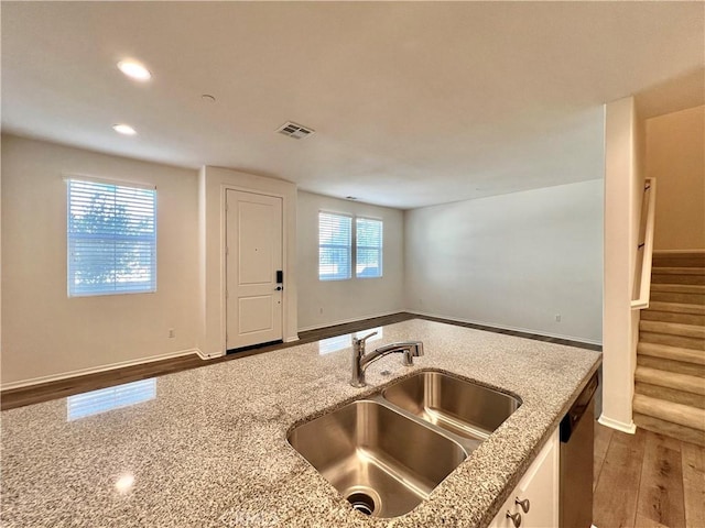 kitchen featuring light stone countertops, sink, a healthy amount of sunlight, and wood-type flooring